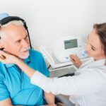 man in blue shirt seeing his audiologist for hearing aid evaluation